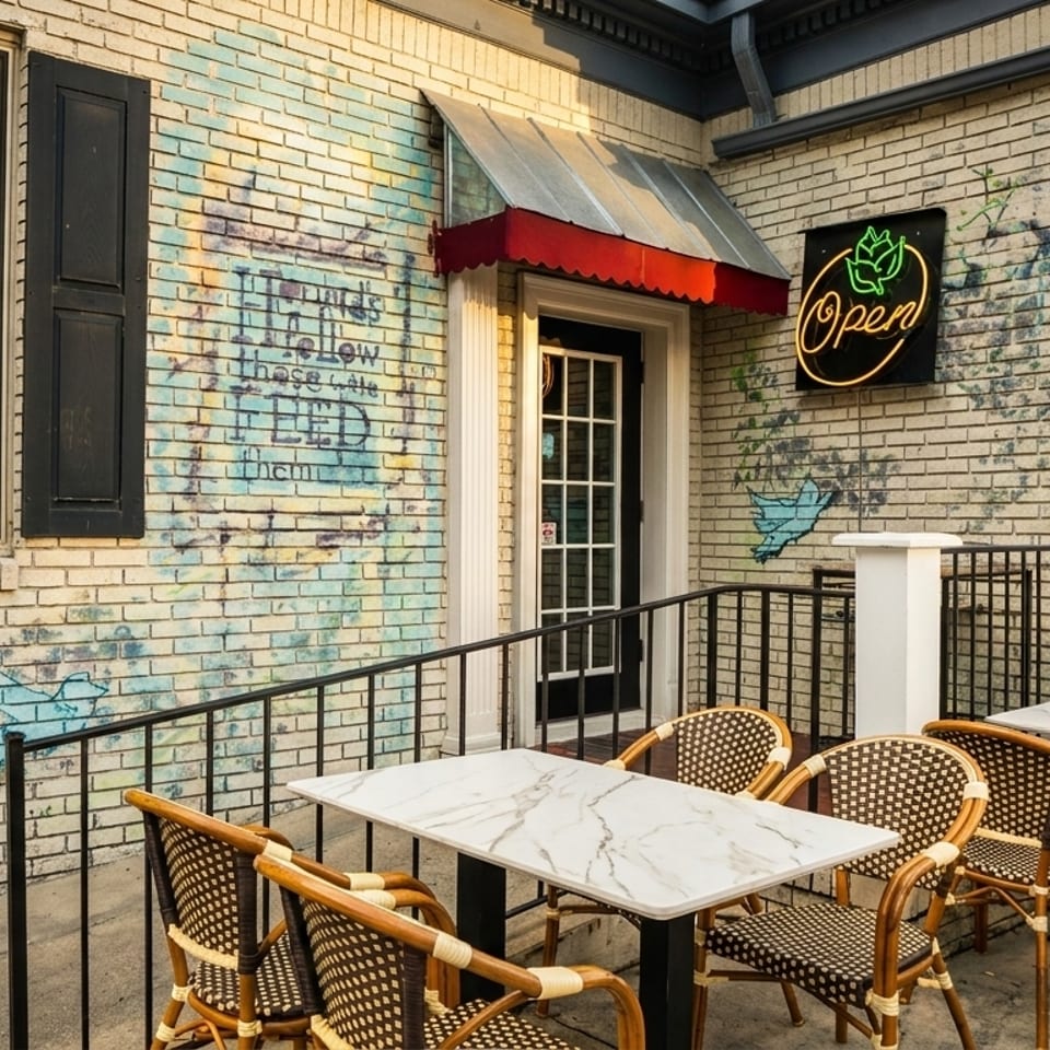 Outdoor patio of Sizzling Spices restaurant with marble tables, wicker chairs, and a neon 'Open' sign.