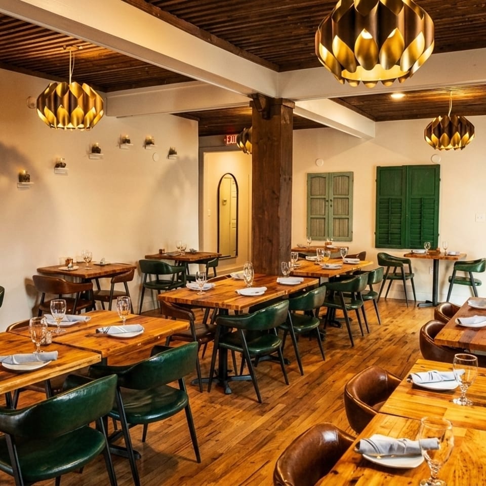 A restaurant dining room with wooden tables, green chairs, and decorative lighting fixtures.